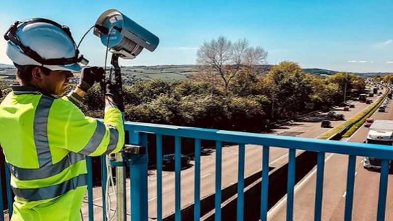 A worker is using a camera on a bridge